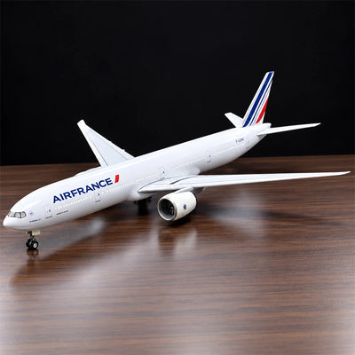 Air France Boeing 777-300ER 1:157 scale aircraft display model with LED cabin lighting, metal stand and wooden base, displayed on a living room table.