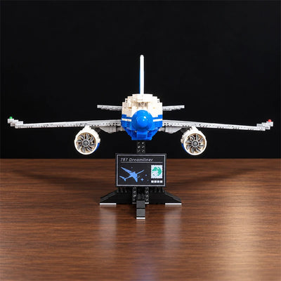 Vue de face d’une maquette du Boeing 787 Dreamliner en briques, avec moteurs détaillés, livrée bleue et blanche et support d’exposition.