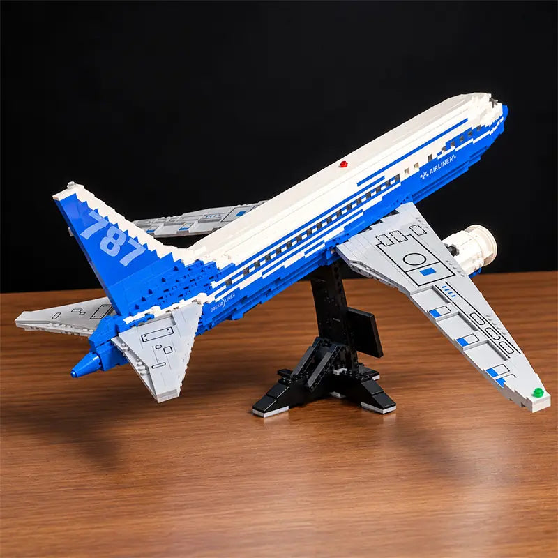 Vue de face d’une maquette du Boeing 787 Dreamliner en briques, avec moteurs détaillés, livrée bleue et blanche et support d’exposition.